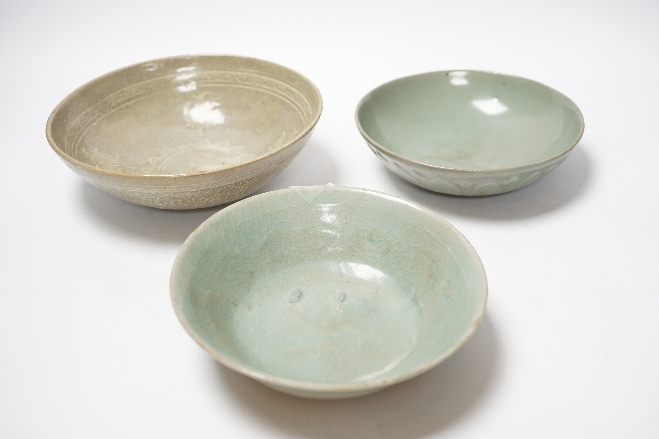 Two Korean celadon bowls, Goryeo dynasty (11th/12th century), the first carved with lotus petals to the underside, the second with fine crackle to the glaze, and a Korean slip-decorated celadon bowl (11th/12th century),